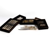 several forks and knives are in a wooden box on a white surface