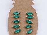 a close up of a pair of green earrings on a cardboard board