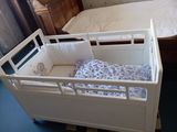 un lit de bébé blanc avec un lit bleu et blanc à l'intérieur