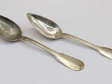 two silver spoons sitting on top of a table next to each other