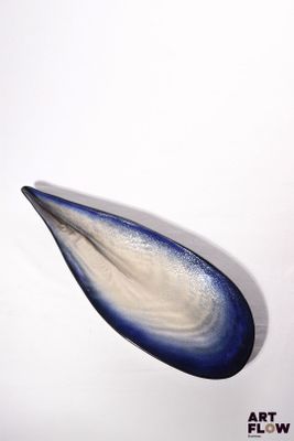 a blue and white glass object on a white surface