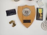 a wooden plaque with a medal on it next to other items