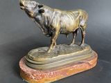 bronze statue of a bull on a marble base on a black background