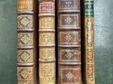 four old books are lined up on a green surface