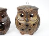 two ceramic owls sitting next to each other on a white surface