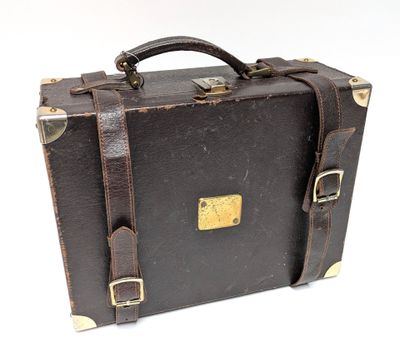une valise marron posée sur une surface blanche