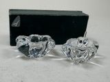 pair of clear glass candlesticks with a black box in the background