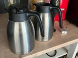 two coffee pots sitting on top of a shelf