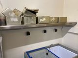 un évier dans un coin de la pièce, avec une étagère en métal au-dessus