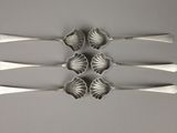 four silver spoons are arranged in a row on a table