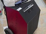 a red and black machine sitting on the floor next to a stack of toilet paper