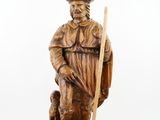 carved wooden statue of a man with a staff and a dog