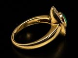 an emerald and diamond ring on a black surface