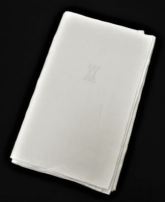 une serviette blanche pliée, ornée d'un monogramme