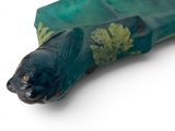 a green object with a fish on it on a white surface