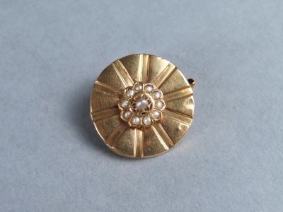 Gros plan sur une broche en or ornée de perles