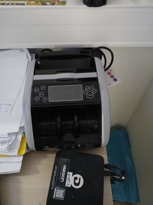 une imprimante posée sur un bureau, à côté d'une pile de papiers