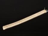 gros plan d'un bracelet en or sur une surface noire