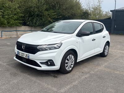 La voiture blanche est garée sur un parking près d'un immeuble.