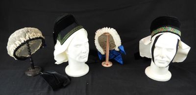 Plusieurs chapeaux sont alignés sur une tête de mannequin, sur fond noir.