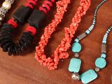 many different necklaces and bracelets on a table