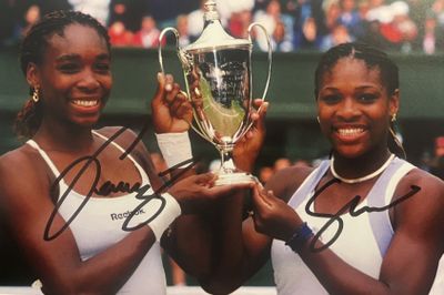 photo dédicacée de deux joueurs de tennis tenant un trophée devant un public