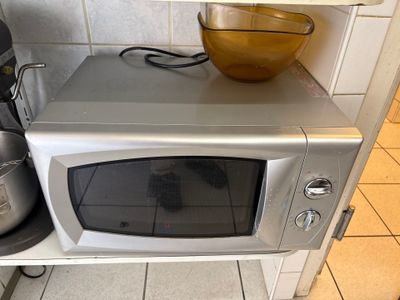 un micro-ondes argenté sur lequel est posé un saladier