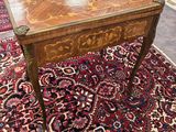 une table ancienne avec un plateau en bois posée sur un tapis dans une pièce