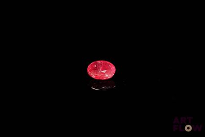 un diamant rouge sur une surface noire dans l'obscurité