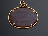 an image of a gold pendant with a brown stone in the center