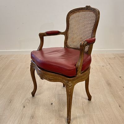 une chaise en bois avec une assise en cuir rouge, posée sur un parquet en bois dur