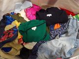 un tas de vêtements dans un bac en plastique posé par terre