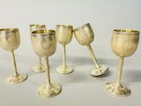 six silver goblets are lined up in a row on a white surface
