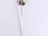 a small metal object on a white surface with a toothpick in it