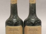 deux bouteilles de vin posées l'une à côté de l'autre sur une surface blanche