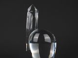 a glass vase with a bird on it on a black surface