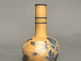a yellow vase with blue flowers on it on a gray surface