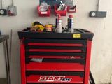 une armoire à outils rouge, sur laquelle sont posés des outils, dans un garage