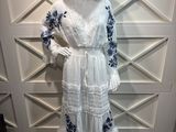 Le mannequin porte une robe blanche et un chapeau de paille.