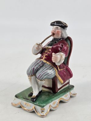 a figurine of a man sitting on a chair smoking a pipe