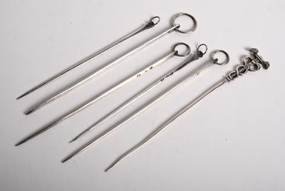 five pairs of surgical instruments are lined up on a white surface