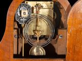 a small wooden clock with a pendulum inside of it