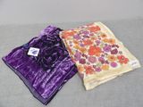 two pieces of purple and orange floral fabric on a gray surface