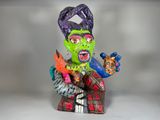 une figurine représentant une femme au visage vert et aux cheveux violets