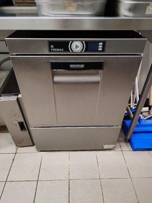 lave-vaisselle en acier inoxydable dans une cuisine professionnelle, avec des bacs bleus en arrière-plan
