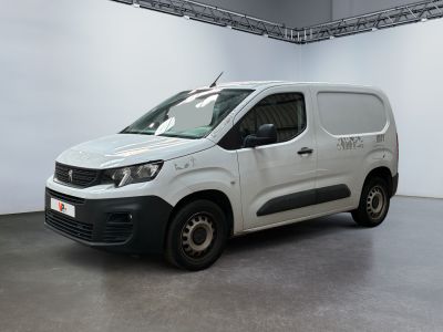 La camionnette blanche est garée dans une grande pièce aux murs blancs.