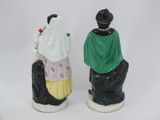 pair of ceramic figurines of a man and a woman sitting on a rock