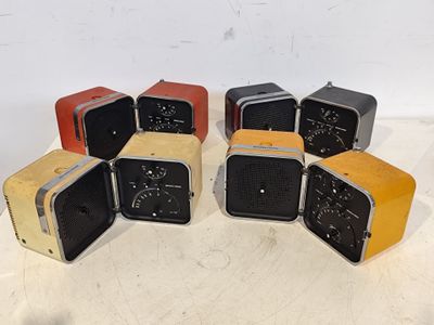 Six radios anciennes sont disposées en cercle sur une table