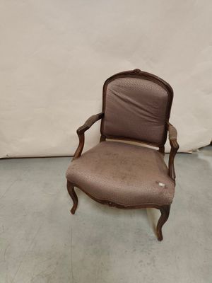 une vieille chaise dont le dossier est recouvert d'un tissu marron et l'assise d'un tissu beige clair