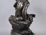 a bronze statue of a man sitting on a rock with a bird in his hand